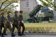 This file photo taken on April 9, 2013 shows officers of Japan's Ground Self-Defense Force (SDF) walking in front of Patriot Advanced Capability-3 (PAC-3) surface-to-air missile launchers, on the grounds of the Defence Ministry in Tokyo.  Photo: AFP