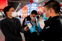A person wearing a face mask displays a green QR code on his phone to show his health status to security at a train station in Wenzhou, China. Photo: AFP