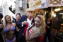 An impersonator of Republican presidential candidate Donald Trump pretends to give a hot dog to a woman near Trump Tower as part of an outdoor performance in connection with work by artist Alison Jackson in New York, New York, USA, on 25 October 2016. The performance, which was made up of the impersonator being surrounded by women in bathing suits pretending to protest him, appeared to be critical of Trump's statements about women. Photo: Justin Lane/EPA
