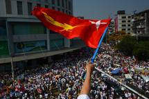 (File) A protester waves the National League for Democracy (NLD) flag while others take part in a demonstration against the military coup in Yangon on February 22, 2021. Photo: AFP