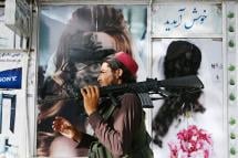 A Taliban fighter walks past a beauty saloon with images of women defaced using a spray paint in Shar-e-Naw in Kabul on August 18, 2021. Photo: Wakil Kohsar/AFP