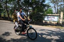 People wearing face mask as a preventive measure against the COVID-19 novel coronavirus, rides past Waibagi Hospital in Yangon that handles patients for isolation on March 24, 2020. Photo: Ye Aung Thu/AFP