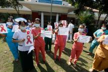 Doctors and nurses from Universities Hospital hold up signs of the red ribbon and placards as they participate in the civil disobedience campaign against the military coup in Yangon, Myanmar, 05 February 2021. Photo: EPA